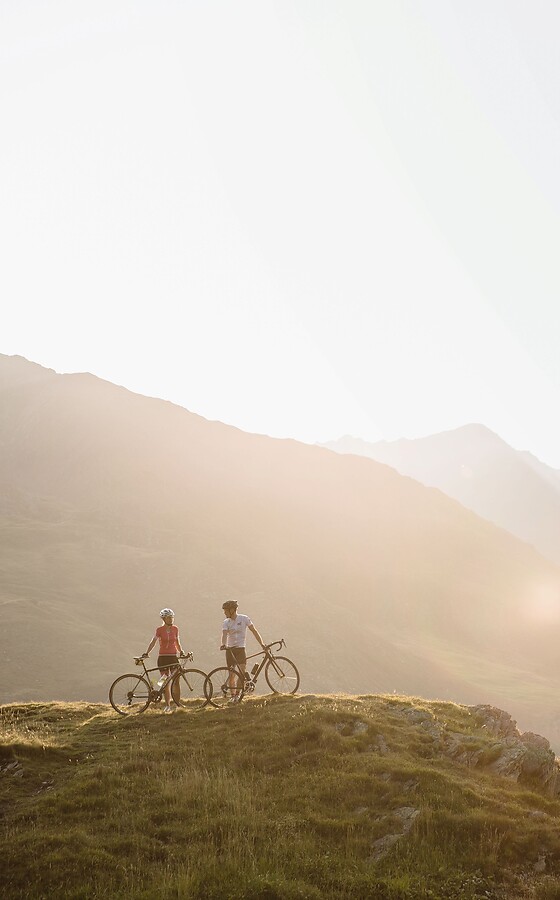 Donna e uomo con bicicletta in montagna al tramonto