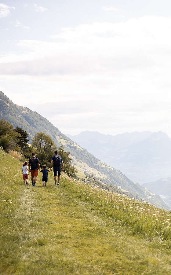 Famiglia che fa escursione in alta montagna con vista sulla valle