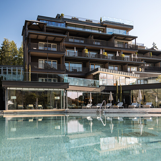 Hotelfassade und Naturpool im Garten