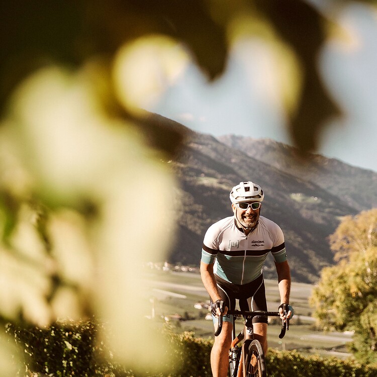Uomo in bici da corsa attraversa i vigneti dell’Alto Adige