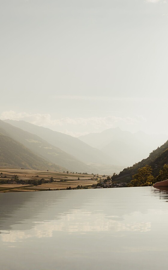 Donna nella piscina a sfioro che guarda la valle aperta