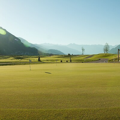Ampio campo da golf al sole con panorama montano