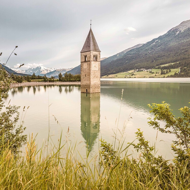 Torre sommersa nel Lago di Resia davanti alle montagne