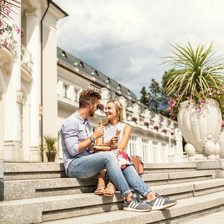 Donna e uomo mangiano gelato sulle scale del Kurhaus nella città termale di Merano
