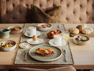 Gedeckter Frühstückstisch mit Eierspeisen, Kaffee und Früchten