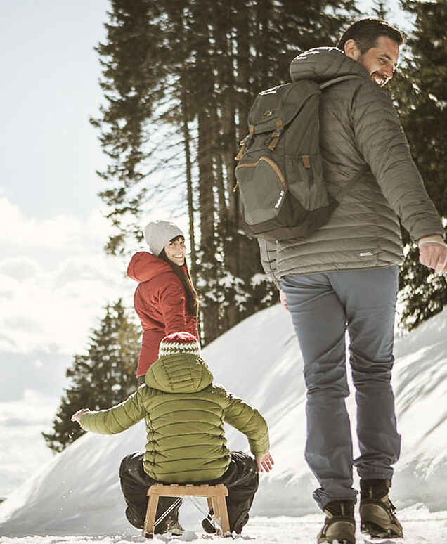 Famiglia che slitta su pista forestale