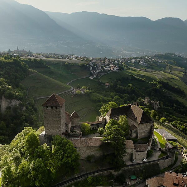 The medieval Tyrol Castle surrounded by mountains and green meadows