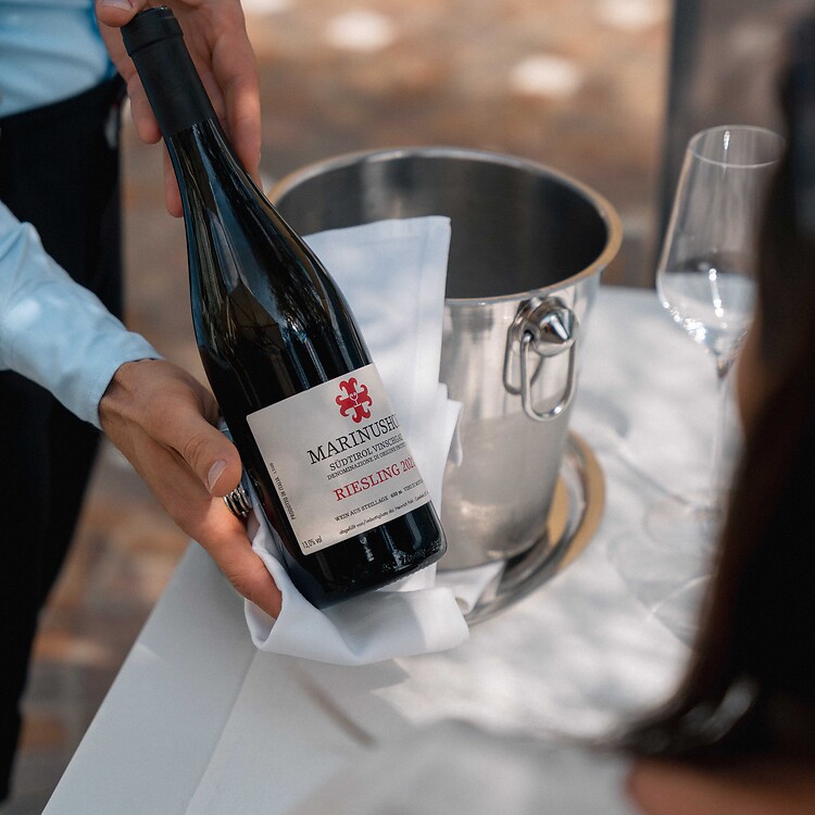 The waiter serves the guest the hotel’s own wine