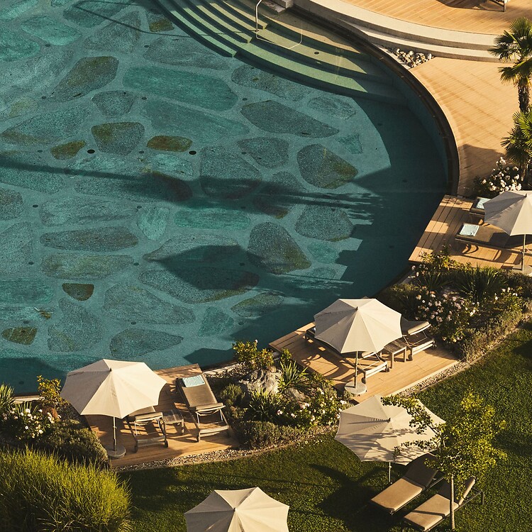Natural pool with sun loungers in the Mediterranean hotel garden