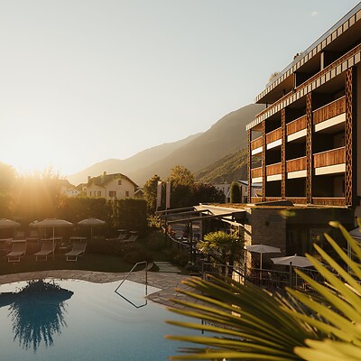 Hotel with outdoor pool and palm trees at sunset