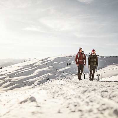 Man and woman in mountains in snow passing chairlift