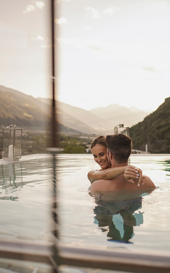 Man and woman hugging in Sky Pool by candlelight with mountain panorama