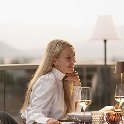 Frau und Mann beim romantischen Candle Light Dinner auf Dachterrasse vor Bergpanorama