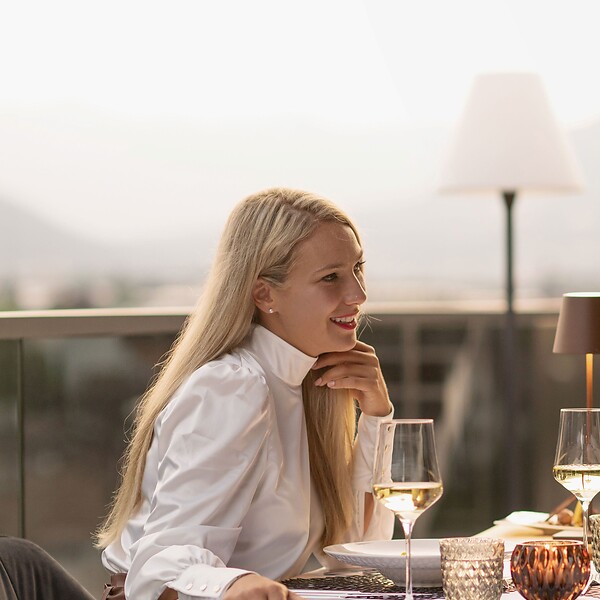 Frau und Mann beim romantischen Candle Light Dinner auf Dachterrasse vor Bergpanorama