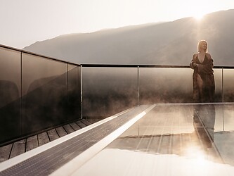 Frau steht am Sky Pool im Sky Spa bei tiefstehender Sonne