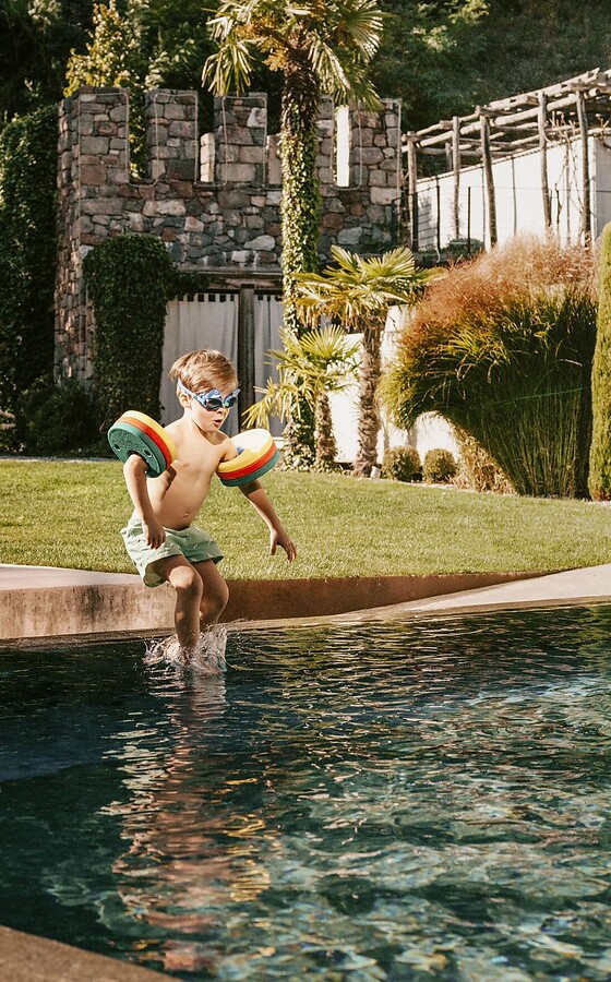 Bub und Mädchen springen in Outdoor Pool im Thermalgarten