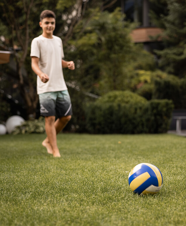 Junge spielt mit Ball im Garten