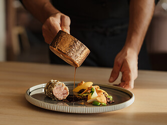 Koch serviert die Sauce zu den Südtiroler Rindswangen