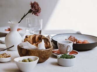 Reichlich gedeckter Frühstückstisch mit frischen Blumen