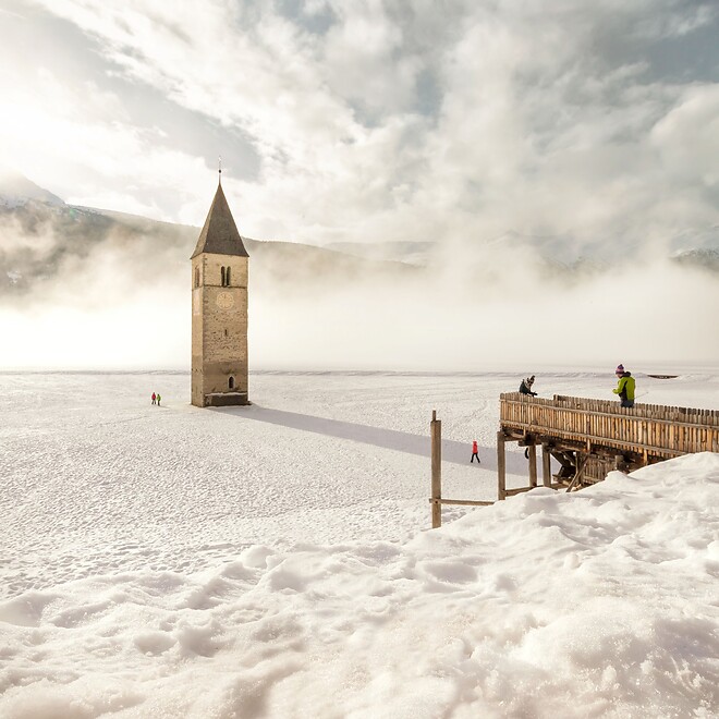 Versunkener Turm im Reschensee bei schneebedeckter Winterlandschaft