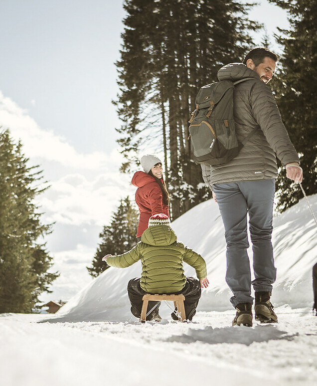 Familie beim Rodeln auf Waldpiste 