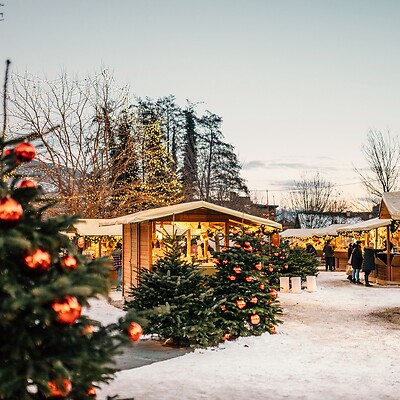 Weihnachtsmarkt mit Ständen aus Holz und geschmückten Bäumen bei Schnee