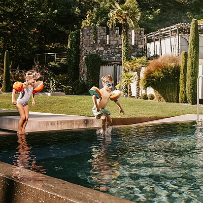 Kinder springen in den Outdoor-Thermalwasserpool