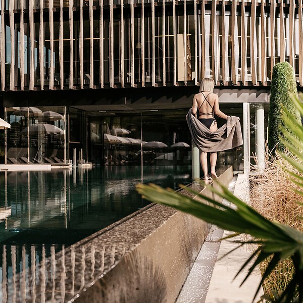 Frau spaziert entlang des Outdoor Pools vor dem Wellnesstower