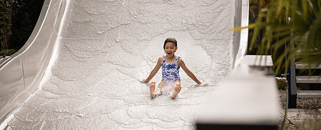 Mädchen auf der Wellenrutsche im Garten