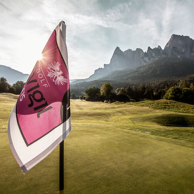 Fahne auf Golfplatz vor Dolomiten bei Sonnenaufgang