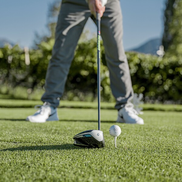 Mann hält Golfschläger an Golfball bereit zum Abschlag