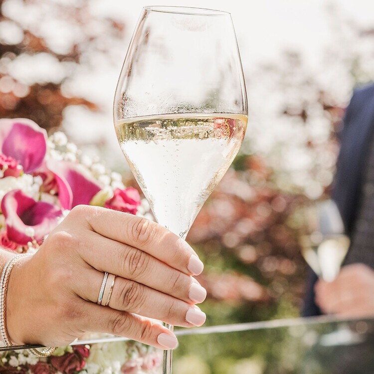 Uomo e donna in abiti da matrimonio al ricevimento con champagne