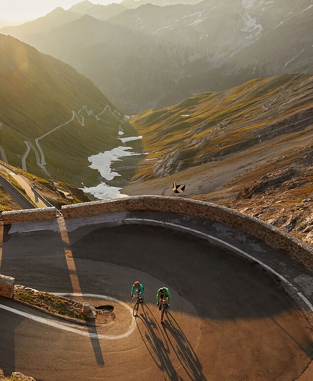 Cyclists riding the switchbacks of Stelvio Pass in the low evening sun