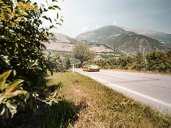 Gelbes Porsche Cabrio auf Straße inmitten der Alpen