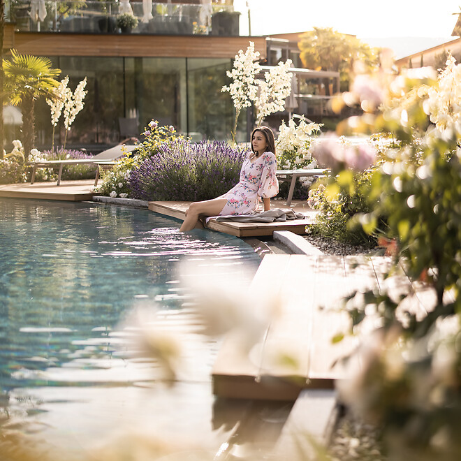 Frau sitz am Naturpool im mediterranen Garten