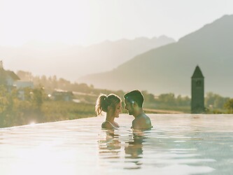 Mann und Frau in Sky Infinity Pool bei romantischem Abendlicht