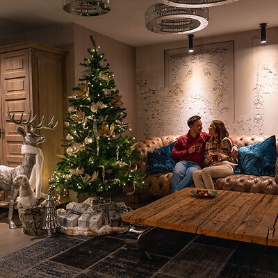 Frau und Mann auf dem Sofa neben dem geschmückten weihnachtsbaum