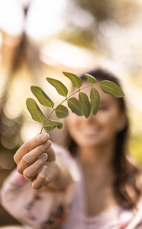 Frau im Hotelgarten und hält Blatt in der Hand