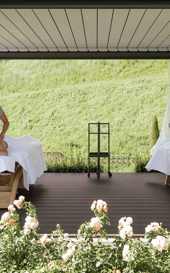 Donna e uomo massaggiati nel padiglione del giardino tra fiori in fiore