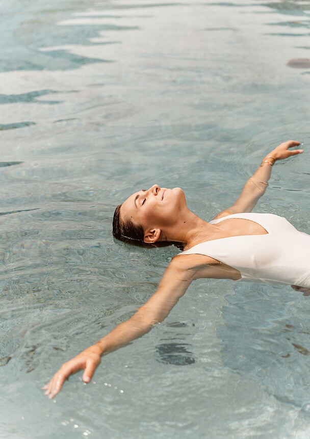 Donna che si lascia galleggiare nell’acqua della piscina naturale