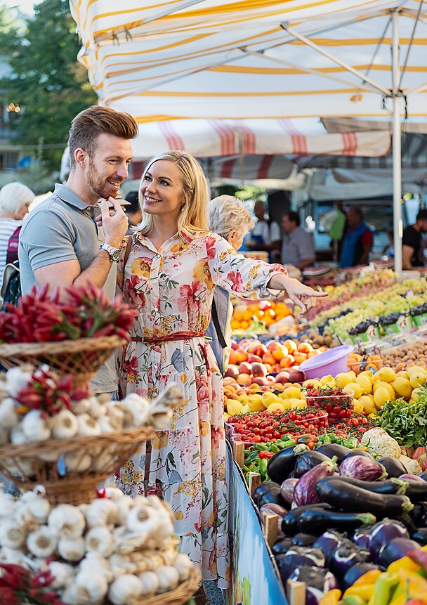 Frau und Mann auf traditionellem Wochemarkt an Gemüsestand 