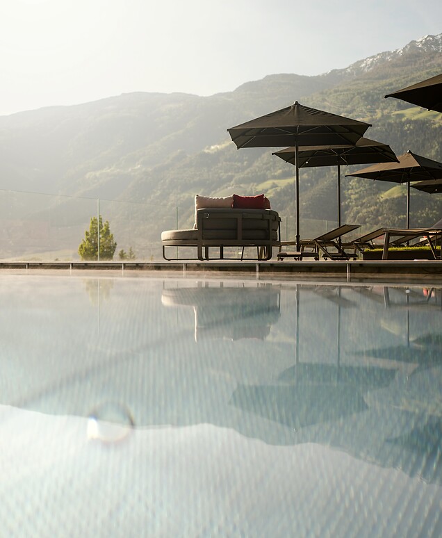 Pool with lounge chair and sun umbrella with mountain views and low sun