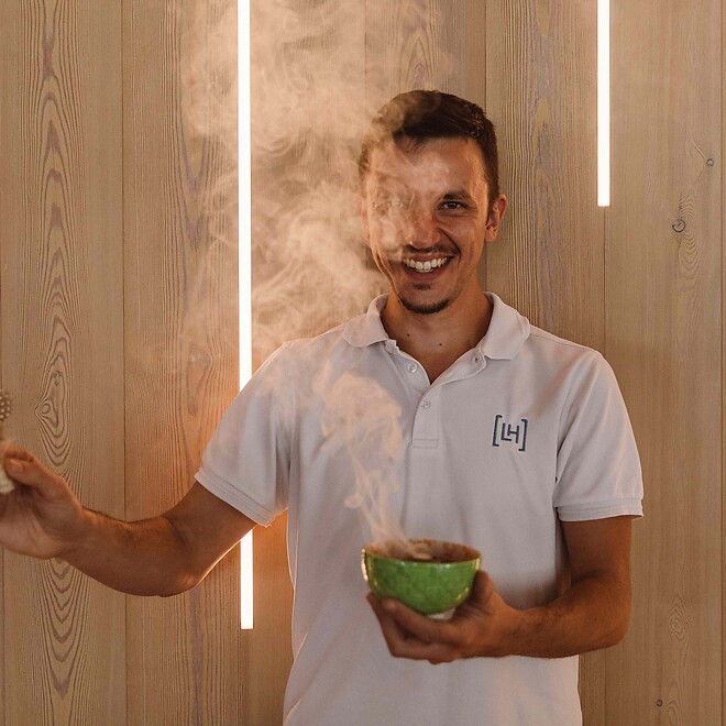 Mann mit dampfender Schüssel zum Räuchern bei Wellnessritualen