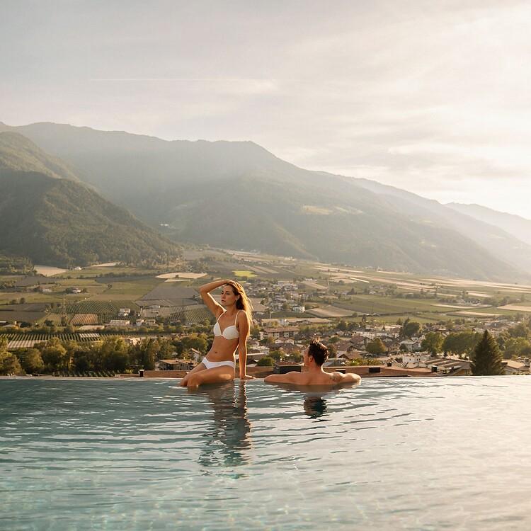 Frau und Mann genießen den Sonnenuntergang am Sky Infinity Sportpool