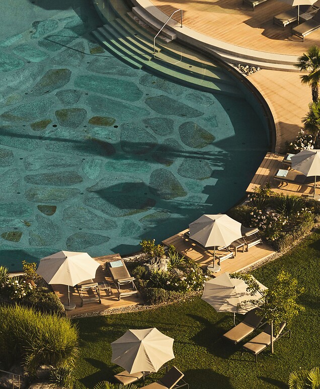 Naturpool mit Sonnenliegen im mediterranem Hotelgarten