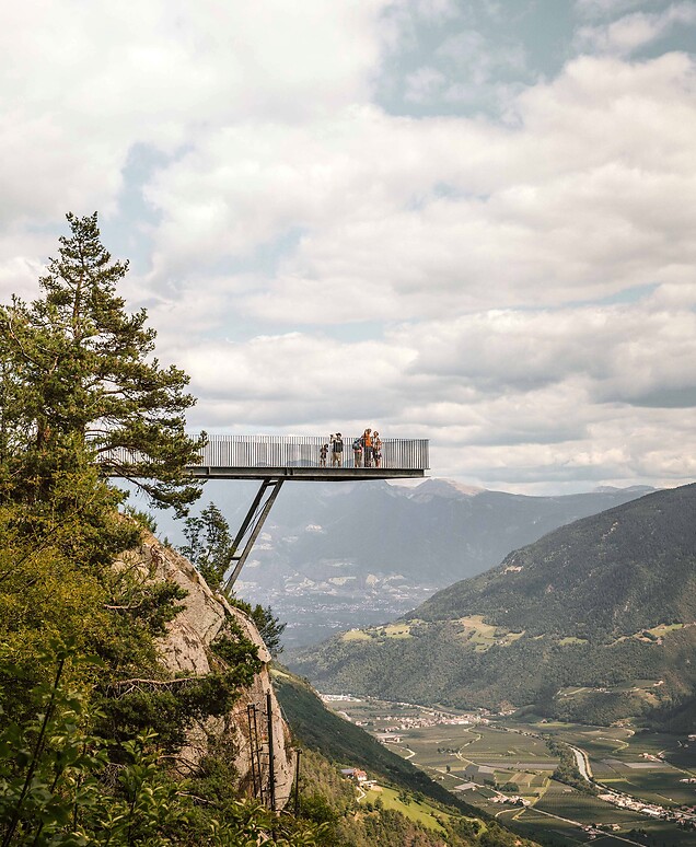 Familie auf Aussichtsplattform in den Bergen mit Blick über weites Tal