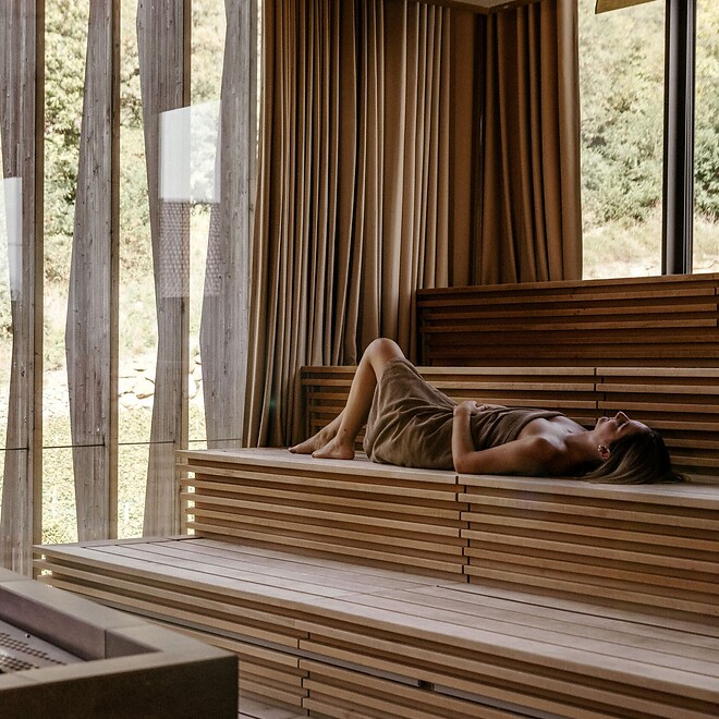 Woman lying in the sauna with a view of the thermal garden