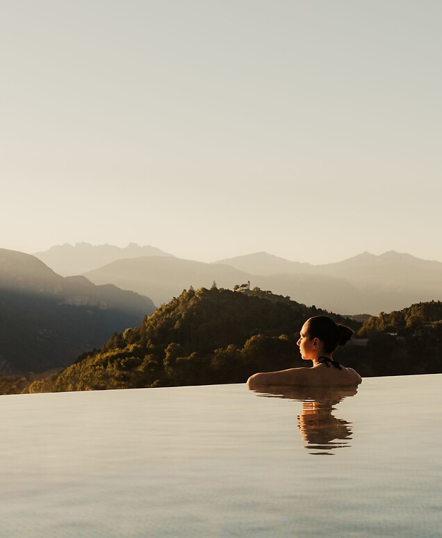 Woman enjoying the view of the Dolomites in the Infinity Skypool at sunrise