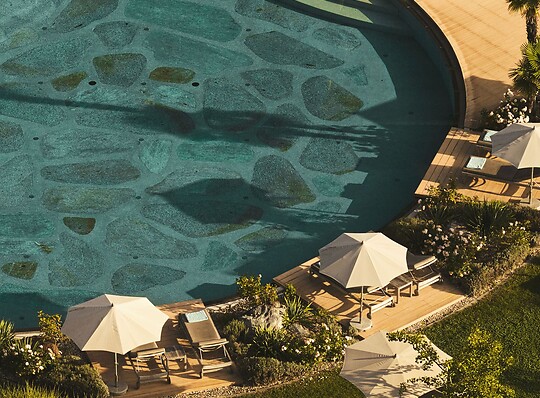 Naturpool mit Sonnenliegen im mediterranem Hotelgarten