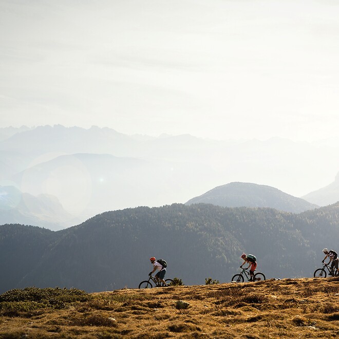 Gruppe fährt mit E-Mountainbikes über Bertrail vor Bergpanorama